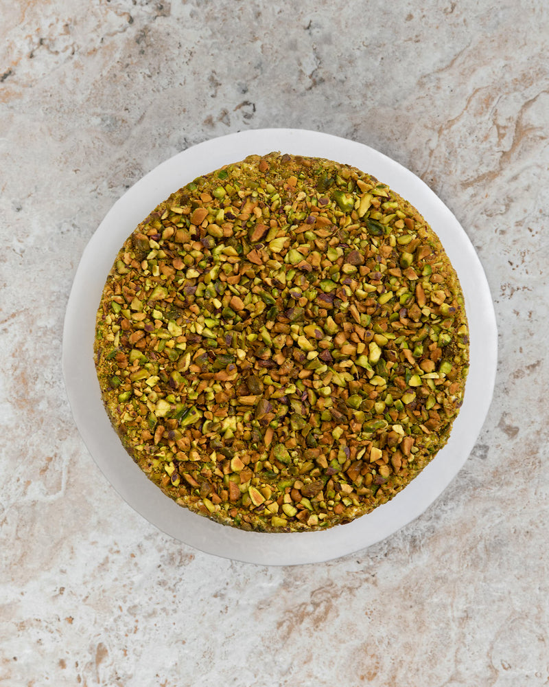 Aerial image of a Pistachio San Rival round cake, covered in pistachio nuts. 