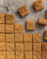 Thirty-six squared golden brown Caramel Bars with four pieces displayed, showing the texture of the bars. 