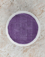 Aerial image of a Ube San Rival round cake, frosted with Ube buttercream and vertical and horizontal streaks for decoration.