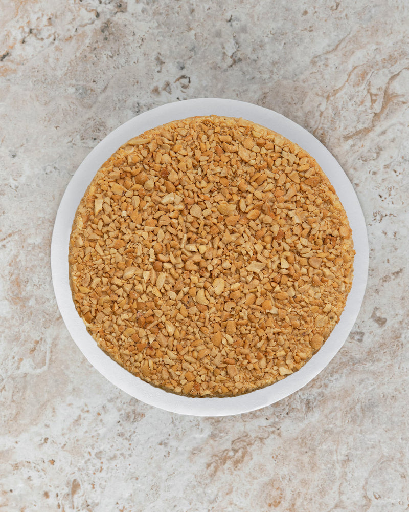 Aerial image of a Cashew San Rival round cake covered in roasted cashew nuts. 