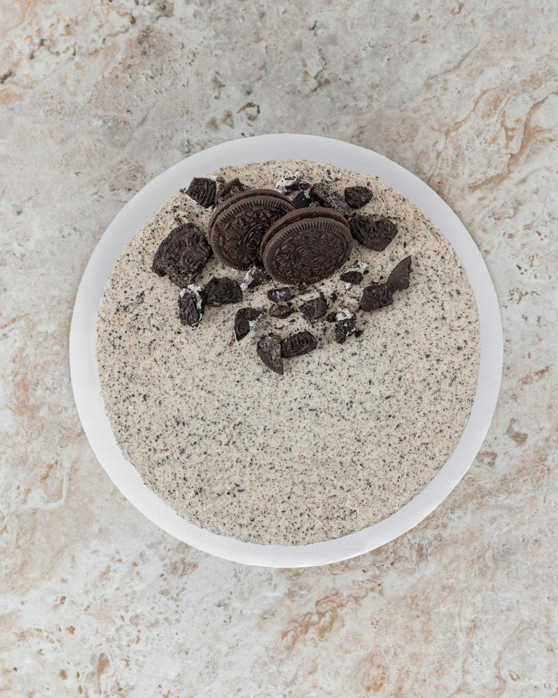 xAerial image of a Cookies and Cream San Rival round cake, covered with Oreo buttercream, topped with two Oreos and crushed Oreos.