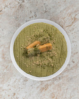 Aerial image of a green Matcha San Rival round cake, frosted with matcha buttercream topped with two vanilla wafers and crushed graham. 